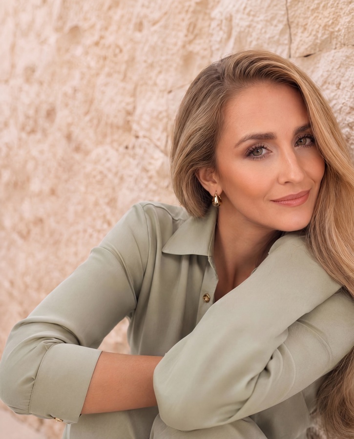 Jennifer Heinz in a sage blouse against a stone wall